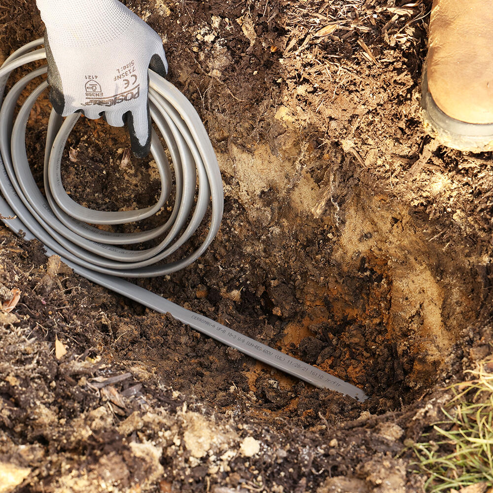 underground feed cable being placed in a dirt trench.